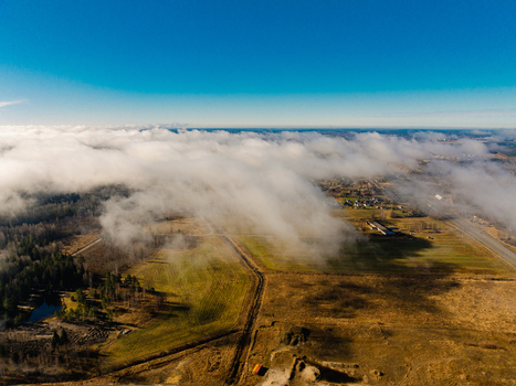 Aerial view of low hanging clouds drifting over rural fields and the A8 highway in Olaine parish Olaine Municipality Latvia. Aerial view of low hanging clouds drifting over rural fields and the A8 highway in Olaine parish Olaine Municipality Latvia.