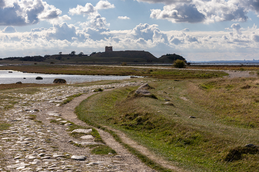 View of the historic ruins of Kalo Castle situated on a hill overlooking the coastal landscape with a cobblestone path in the foreground in Ronde Jutland Denmark. View of the historic ruins of Kalo Castle situated on a hill overlooking the coastal landscape with a cobblestone path in the foreground in Ronde Jutland Denmark.