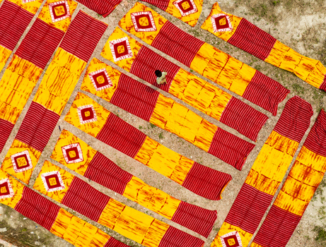 Narayanganj Bangladesh 30 March 2026 Aerial view of meticulously arranged textiles displaying vibrant patterns of red and yellow creating a visually striking geometric landscape.