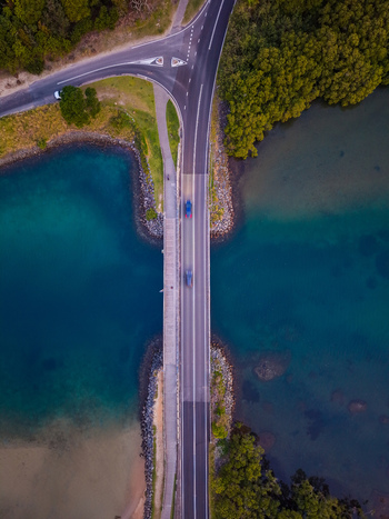 Aerial view of Cudgen Creek bridge with cars driving across the asphalt road surrounded by turquoise water and lush green mangroves in Tweed Shire Council New South Wales Australia.