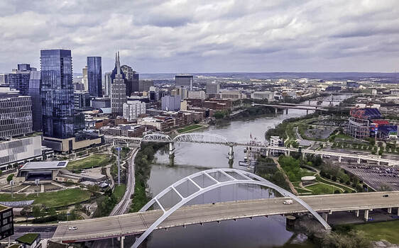Aerial view of Downtown Nashville skyline featuring the Cumberland River the Korean Veterans Memorial Bridge and modern skyscrapers under a cloudy sky in Nashville Tennessee United States. Aerial view of Downtown Nashville skyline featuring the Cumberland River the Korean Veterans Memorial Bridge and modern skyscrapers under a cloudy sky in Nashville Tennessee United States.