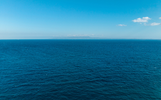 Aerial view of the deep blue ocean stretching to the horizon under a clear sky in Kecamatan Dawan Bali Indonesia. Aerial view of the deep blue ocean stretching to the horizon under a clear sky in Kecamatan Dawan Bali Indonesia.
