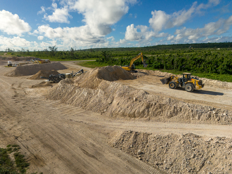 Aerial view of the restoration of North Field Base showing industrial equipment large sand piles and dirt roads in Northern Tinian Tinian Northern Mariana Islands.