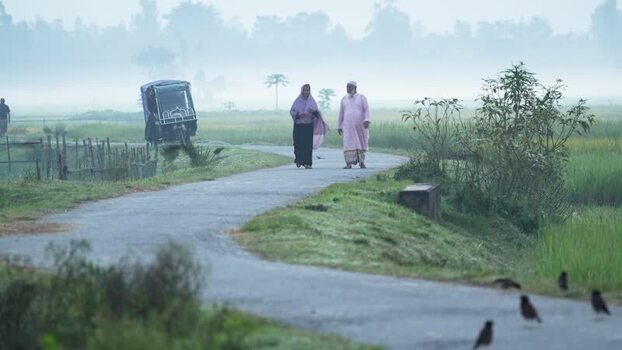 View of a man and woman walking on a misty road Bangladesh.
