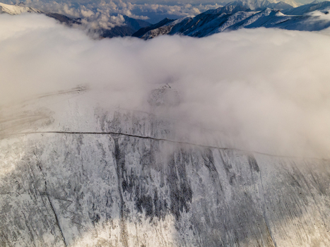 Aerial view of the snow covered Babusar Pass with a winding road cutting through the mountain slopes under thick white clouds Babusar KPK Pakistan.