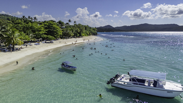 Aerial view of Javo Beach La Playita featuring turquoise water white sand lush tropical trees and boats in Las Galeras Las Galeras Dominican Republic. Aerial view of Javo Beach La Playita featuring turquoise water white sand lush tropical trees and boats in Las Galeras Las Galeras Dominican Republic.