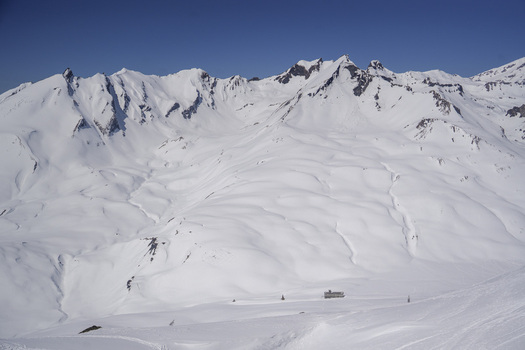 Aerial view of Colle del Piccolo San Bernardo with snow covered mountain peaks and alpine slopes under a clear blue sky in La Thuile Valle d Aosta Italy. Aerial view of Colle del Piccolo San Bernardo with snow covered mountain peaks and alpine slopes under a clear blue sky in La Thuile Valle d Aosta Italy.