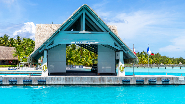 View of the Bora Bora dock terminal with its thatched roof structure and turquoise lagoon waters Bora Bora Leeward Islands French Polynesia.