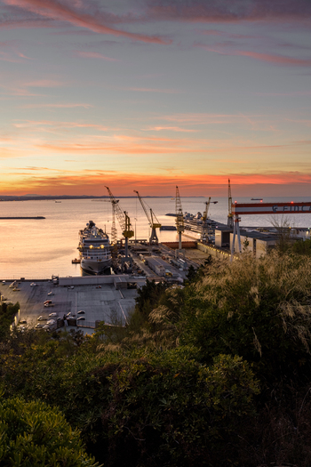 Aerial view of Ancona Port at sunset with a large cruise ship docked at the shipyard industrial cranes and calm waters under a vibrant orange sky in Ancona Marche Italy. Aerial view of Ancona Port at sunset with a large cruise ship docked at the shipyard industrial cranes and calm waters under a vibrant orange sky in Ancona Marche Italy.