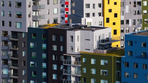Aerial view of a modern apartment complex featuring vibrant multi colored facades in shades of blue yellow green and grey with balconies and green roofs in Iceland. Aerial view of a modern apartment complex featuring vibrant multi colored facades in shades of blue yellow green and grey with balconies and green roofs in Iceland.