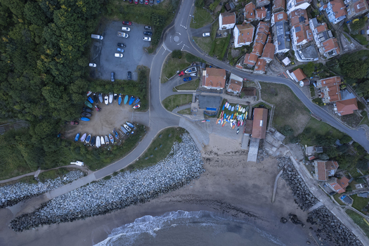 Aerial view of Runswick Bay featuring a small harbor with colorful boats stored on the beach a parking area and surrounding coastal village houses in Runswick Bay England United Kingdom. Aerial view of Runswick Bay featuring a small harbor with colorful boats stored on the beach a parking area and surrounding coastal village houses in Runswick Bay England United Kingdom.