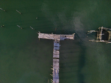 Aerial view of the weathered wooden pier at Galang Baru with its T shaped structure over calm green water Galang Riau Islands Indonesia. Aerial view of the weathered wooden pier at Galang Baru with its T shaped structure over calm green water Galang Riau Islands Indonesia.