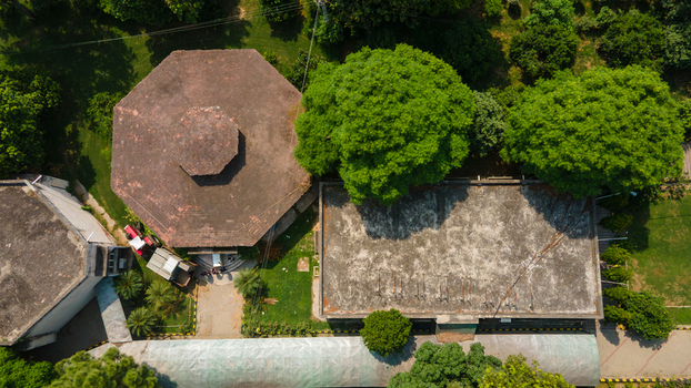 Lahore Punjab Pakistan 08 September 2026 Aerial view of a government office building with an octagonal roof and flat rectangular section surrounded by lush trees and lawns.