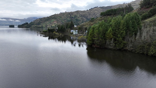 Aerial view of Corani Lake surrounded by lush pine forests and rolling hills under a cloudy sky in Chapare Cochabamba Department Bolivia. Aerial view of Corani Lake surrounded by lush pine forests and rolling hills under a cloudy sky in Chapare Cochabamba Department Bolivia.