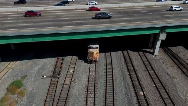 Aerial view of freight train under highway bridge United States.