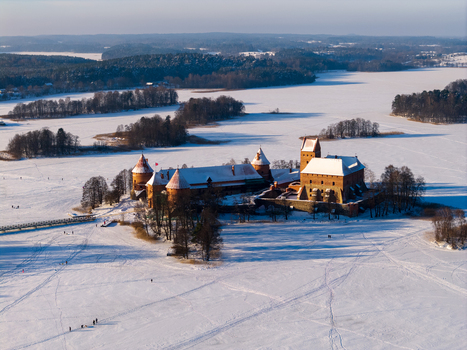 Aerial view of the historic Trakai Island Castle surrounded by a frozen lake and snow covered landscape during winter in Trakai Vilniaus apskritis Lithuania.