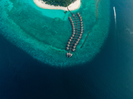 Aerial view of overwater bungalows on a bright turquoise reef beside a white sand island and dark blue ocean Hoarafushi Thiladhunmathee Uthuruburi Maldives. Aerial view of overwater bungalows on a bright turquoise reef beside a white sand island and dark blue ocean Hoarafushi Thiladhunmathee Uthuruburi Maldives.