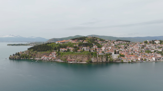 Aerial view of the historic town of Ohrid with red tiled rooftops perched on a rocky cliff overlooking the calm waters of Lake Ohrid in Ohrid Municipality of Ohrid North Macedonia. Aerial view of the historic town of Ohrid with red tiled rooftops perched on a rocky cliff overlooking the calm waters of Lake Ohrid in Ohrid Municipality of Ohrid North Macedonia.