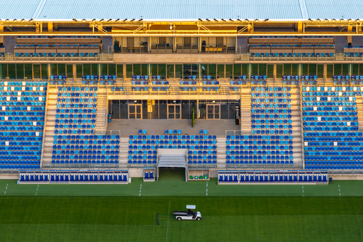 Aerial view of the football stadium with rows of blue seats and a maintenance vehicle on the green pitch in Plock Mazowieckie Poland.