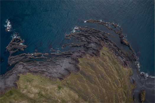 Aerial view of the rugged volcanic coastline and black rock formations of Djupalonssandur meeting the dark ocean in Iceland. Aerial view of the rugged volcanic coastline and black rock formations of Djupalonssandur meeting the dark ocean in Iceland.