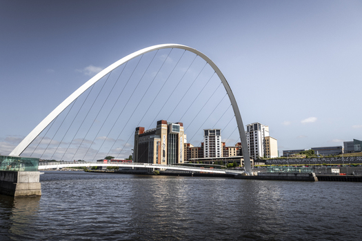 View of the Gateshead Millennium Bridge spanning the River Tyne with modern architecture and a clear blue sky in Newcastle upon Tyne England United Kingdom. View of the Gateshead Millennium Bridge spanning the River Tyne with modern architecture and a clear blue sky in Newcastle upon Tyne England United Kingdom.