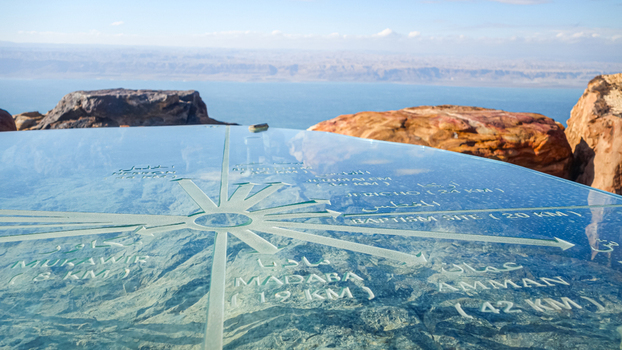View of the glass compass orientation marker at the Mount Nebo viewpoint overlooking the rugged landscape and the Dead Sea in Madaba Madaba Governorate Jordan. View of the glass compass orientation marker at the Mount Nebo viewpoint overlooking the rugged landscape and the Dead Sea in Madaba Madaba Governorate Jordan.