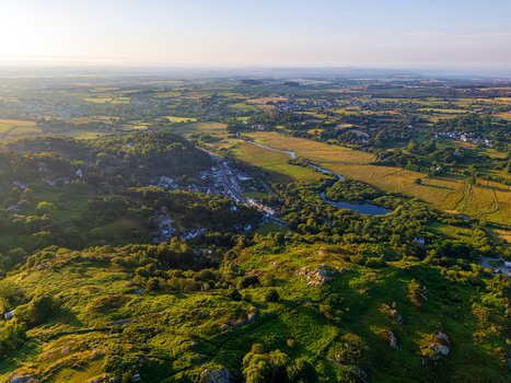 Aerial view of the village of Cwm y glo nestled among lush green hills trees and a small lake under the warm glow of the golden hour in Cwm y glo Wales United Kingdom. Aerial view of the village of Cwm y glo nestled among lush green hills trees and a small lake under the warm glow of the golden hour in Cwm y glo Wales United Kingdom.