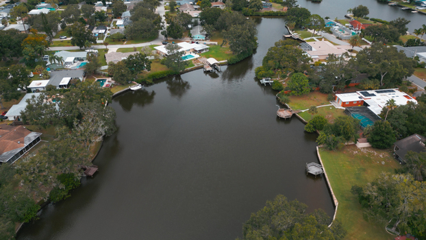Aerial view of a residential neighborhood featuring a canal with private docks and houses with swimming pools in Clearwater Florida United States.