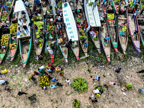 Rangamati Hill District Bangladesh 18 May 2024 Aerial view of Kaptai Lake featuring a bustling floating market with wooden boats loaded with jackfruit and fresh produce with vendors and customers.