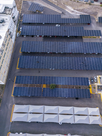 Aerial view of a large parking lot featuring extensive solar panel carports providing shade for parked vehicles in an urban environment in Chihuahua Chihuahua Mexico. Aerial view of a large parking lot featuring extensive solar panel carports providing shade for parked vehicles in an urban environment in Chihuahua Chihuahua Mexico.