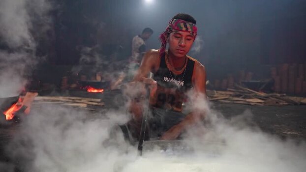 View of a worker stirring a pot in a smoky workshop Bangladesh. View of a worker stirring a pot in a smoky workshop Bangladesh.