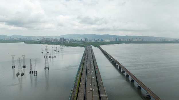 Aerial view of Vashi bridge spanning the creek with traffic electricity pylons in the water and the Navi Mumbai skyline in Navi Mumbai Maharashtra India.