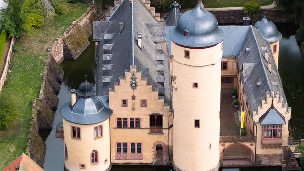 Aerial view of Schloss Mespelbrunn a historic water castle with distinctive towers steep gabled roofs and surrounding moat in Mespelbrunn Bayern Germany. Aerial view of Schloss Mespelbrunn a historic water castle with distinctive towers steep gabled roofs and surrounding moat in Mespelbrunn Bayern Germany.