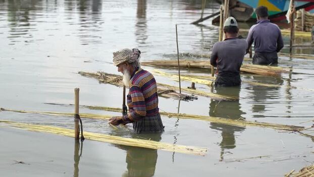 View of men processing jute fibers in water Bangladesh.
