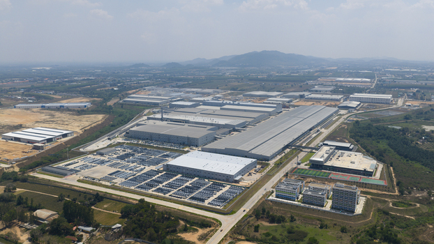 Aerial view of the BYD Auto Thailand factory complex featuring large industrial buildings and extensive parking lots with new vehicles in Phananikhom Rayong Thailand.