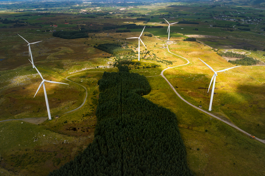 Aerial view of Hog Jaeren Wind Farm with large wind turbines set in a rolling green landscape with patches of forest and winding roads in Ha Municipality Rogaland Norway.