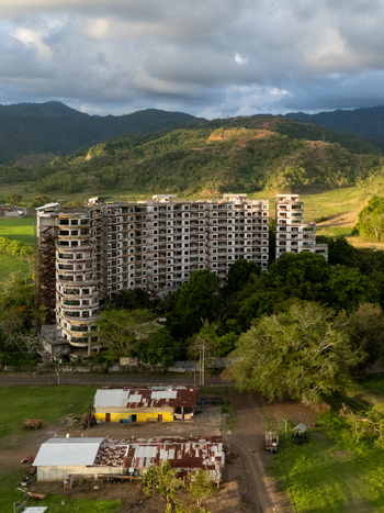 Aerial view of the abandoned Sonesta One Resort building surrounded by lush tropical vegetation and green hills under a cloudy sky in Jaco Provincia de Puntarenas Costa Rica. Aerial view of the abandoned Sonesta One Resort building surrounded by lush tropical vegetation and green hills under a cloudy sky in Jaco Provincia de Puntarenas Costa Rica.