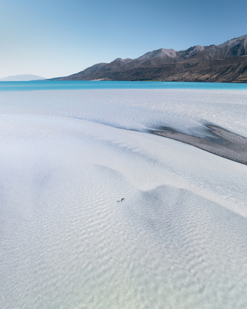 Aerial view of turquoise waters meeting pale shores under a clear sky framed by distant mountains Lake Tekapo Canterbury Region New Zealand. Aerial view of turquoise waters meeting pale shores under a clear sky framed by distant mountains Lake Tekapo Canterbury Region New Zealand.