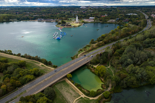 Aerial view of Willen Lake with its water sports facilities a bridge crossing the water and surrounding greenery in Broughton England United Kingdom. Aerial view of Willen Lake with its water sports facilities a bridge crossing the water and surrounding greenery in Broughton England United Kingdom.