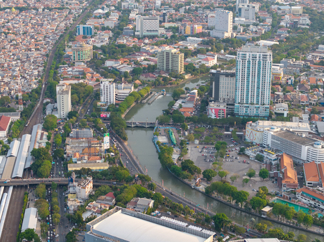 Surabaya Indonesia 28 August 2026 Aerial view of the Kalimas River flowing through Surabaya East Java surrounded by high rise buildings dense urban housing and green trees.