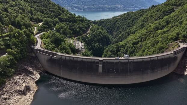 Aerial view of the Verzasca Dam and lush green mountains Switzerland.
