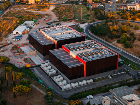 Aerial view of a modern datacenter facility with large rectangular buildings rooftop HVAC units and surrounding infrastructure in Settecamini Lazio Italy.
