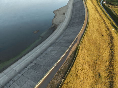 Aerial view of the concrete embankment of Lake Czorsztynskie with a grassy slope illuminated by golden hour light in Nowy Targ Lesser Poland Voivode Poland.