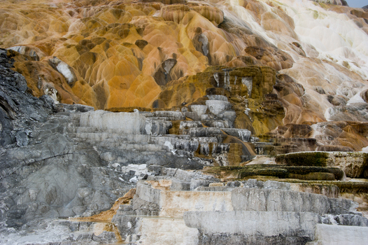 View of the colorful travertine terraces at Mammoth Hot Springs with mineral deposits and layered rock formations in Yellowstone National Park United States.