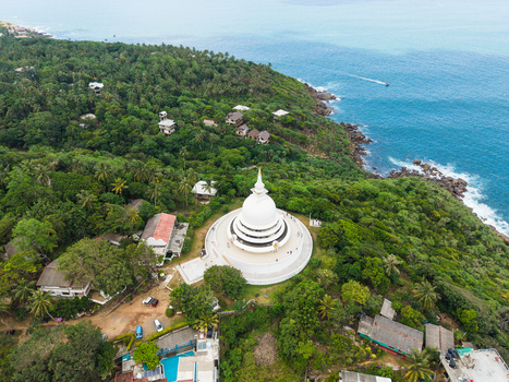 Aerial view of the Japanese Peace Pagoda Rumassala a white stupa surrounded by lush tropical forest and the blue ocean coastline in Unawatuna Southern Province Sri Lanka. Aerial view of the Japanese Peace Pagoda Rumassala a white stupa surrounded by lush tropical forest and the blue ocean coastline in Unawatuna Southern Province Sri Lanka.