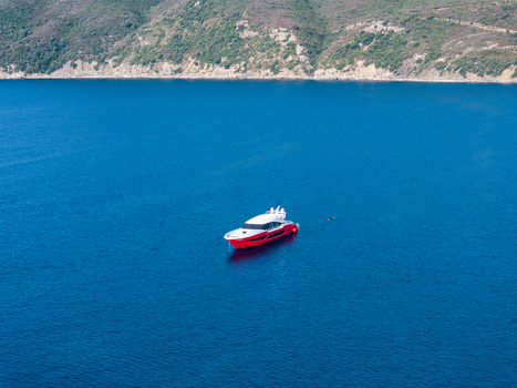 Aerial view of a red luxury pleasure boat anchored in the clear blue waters of Lacona Bay Lacona Tuscany Italy.