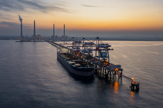 Aerial view of Orot Rabin Power Plant with a large cargo ship docked at the pier during sunset featuring industrial chimneys and cranes in Hadera Haifa District Israel. Aerial view of Orot Rabin Power Plant with a large cargo ship docked at the pier during sunset featuring industrial chimneys and cranes in Hadera Haifa District Israel.
