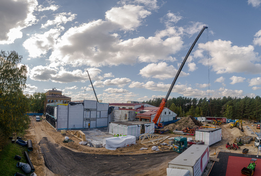 Aerial view of a construction site featuring modular building structures large cranes and heavy machinery under a cloudy sky in Latvia. Aerial view of a construction site featuring modular building structures large cranes and heavy machinery under a cloudy sky in Latvia.