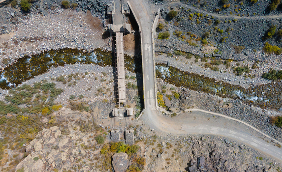 Aerial view of Sadpara Gol featuring a bridge over a flowing stream rocky terrain and surrounding mountainous landscape in Skardu Gilgit Pakistan.