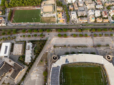 Aerial view of Stadio Riviera delle Palme with its curved roof and green pitch surrounded by urban infrastructure and parking areas in San Benedetto del Tronto Marche Italy.